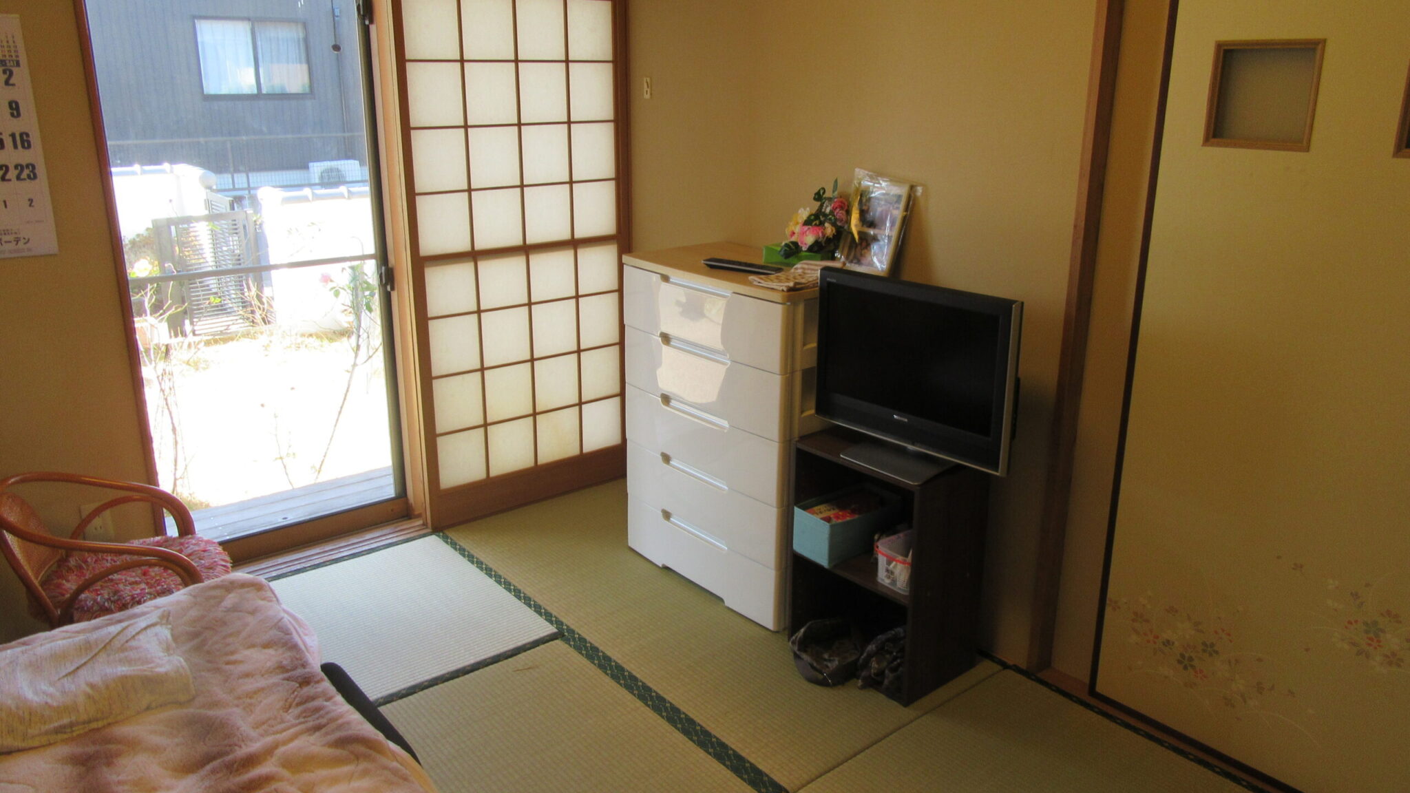 和室の居室。ベッド、テレビ、収納がある明るい部屋